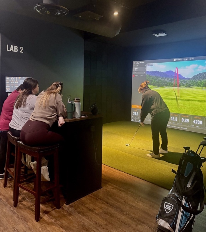 Friends at the high-top in Lab 2 watching a golfer hit an iron