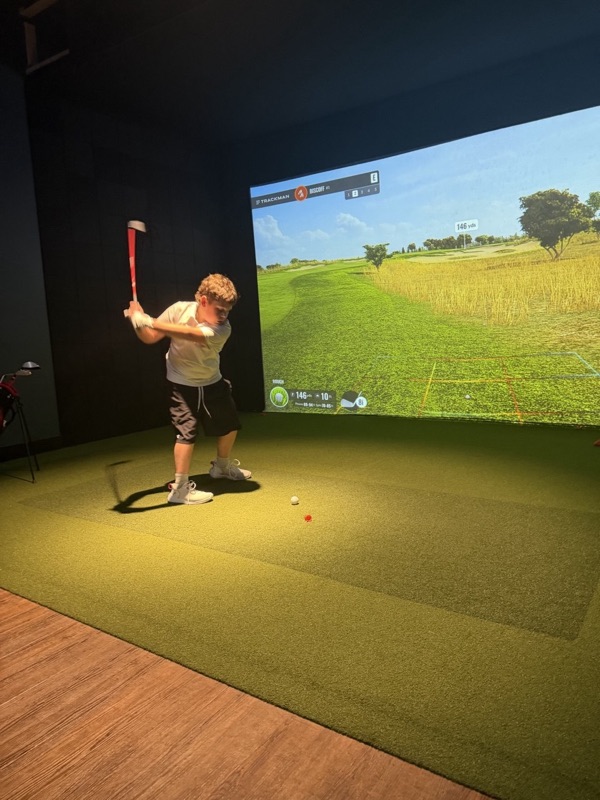 A junior golfer at the top of his backswing, a 146-yard approach on the screen
