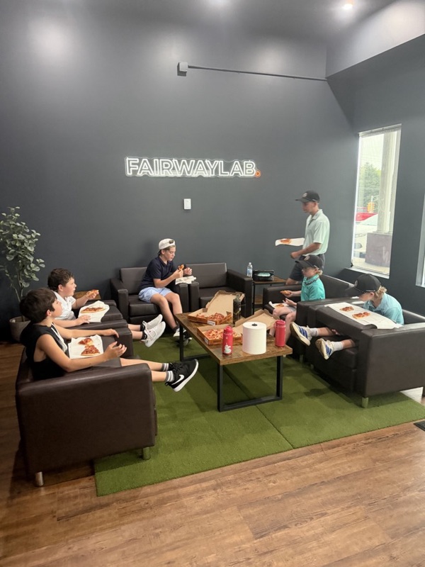 Camp kids eating pizza on the couches in the FAIRWAYLAB lounge